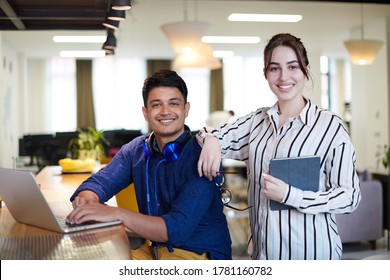 Multiethnic Business People Indian Man With A Female Colleague Working Together On Tablet And Laptop Computer In Relaxation Area Of Modern Startup Office