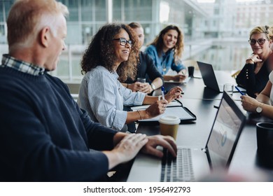 Multi-ethnic business people smiling during a meeting in conference room. Team of professionals having meeting in boardroom.