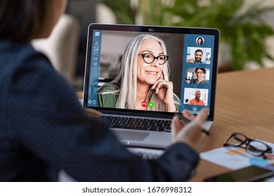 Multiethnic business team having discussion in video call. Rear view of business woman in video conference with boss and his colleagues during online meeting. Senior woman in video call with partners.