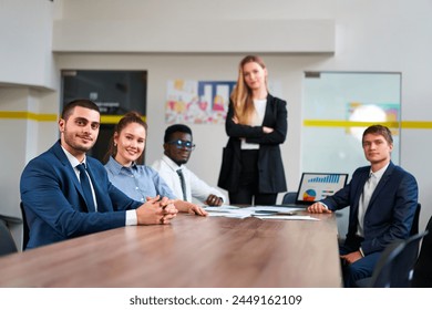 Multiethnic business team sits at table in modern office. Confident diverse group with caucasian, african, arabic in corporate discussion. Colleagues work together on startup strategy. Pro setting. - Powered by Shutterstock