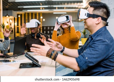 Multiethnic Business Team Using Virtual Reality Headset In Office Meeting. Young Developers Meeting With Virtual Reality Simulator Around Table In Creative Office.