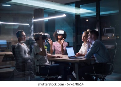 Multiethnic Business team using virtual reality headset in night office meeting  Developers meeting with virtual reality simulator around table in creative office. - Shutterstock ID 677678614