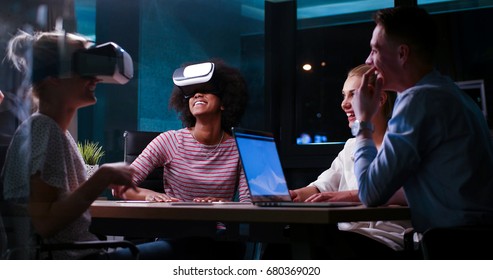 Multiethnic Business team using virtual reality headset in night office meeting  Developers meeting with virtual reality simulator around table in creative office. - Powered by Shutterstock