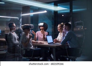 Multiethnic Business team using virtual reality headset in night office meeting  Developers meeting with virtual reality simulator around table in creative office. - Powered by Shutterstock