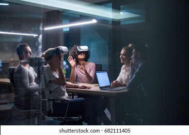 Multiethnic Business Team Using Virtual Reality Headset In Night Office Meeting  Developers Meeting With Virtual Reality Simulator Around Table In Creative Office.