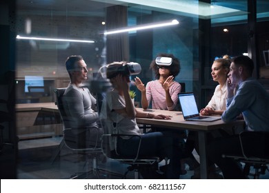 Multiethnic Business Team Using Virtual Reality Headset In Night Office Meeting  Developers Meeting With Virtual Reality Simulator Around Table In Creative Office.