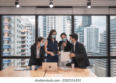 Multiethnic business team wearing face mask during business meeting in new normal office. Diverse corporate colleagues brainstorming with technology device and business paperwork - Powered by Shutterstock