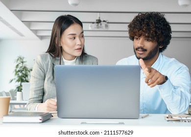 Multi-ethnic Business Team Working Together. Two Creative Workers Discussing Online Startup Project Looking At Laptop Screen. Front View Portrait Of Asian Woman And Indian Man Using Computer