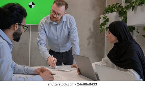 Multiethnic colleagues businessmen and muslim businesswoman in hijab teamwork in office boardroom business team talk brainstorming discussion with green screen interactive board copy space chroma key - Powered by Shutterstock