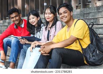 Multiethnic college students reading, preparing for exam or working on group project while sitting on staircase or steps of college campus - Shutterstock ID 2311788281