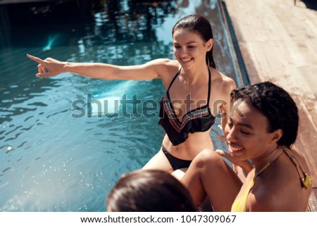 Multiethnic company of beautiful girls is spending vacations by swimming pool. Joyful company spends leisure time in pool.