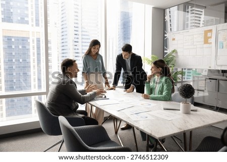 Multiethnic company managers startup developers team with middle aged leader boss gather around boardroom table brainstorming insights creating plans reviewing project materials in modern urban office