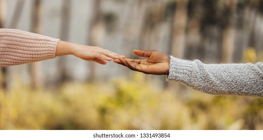 Multi-ethnic Couple Hands Reaching And Touching Outdoors. Couple Approaching To Each Other. Female And Male Hands Touching Each Other By Fingers.