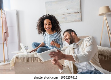 multiethnic couple looking at digital tablet in bedroom - Powered by Shutterstock