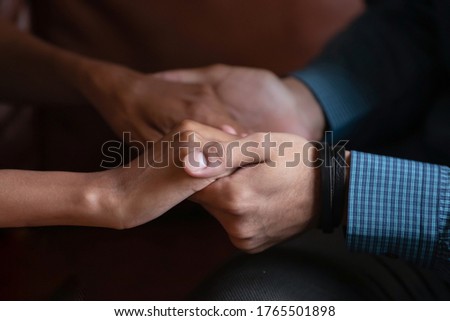 Multiethnic couple in love holding hands close up image. Mixed race woman and caucasian man having heart-to-heart talk showing protection, give psychological aid to friend, declaration of love concept