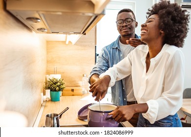 Multiethnic couple preparing lunch together at home. Loving black wife and husband preparing dinner in kitchen. Happy family cooking vegetarian food in loft kitchen