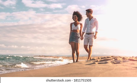 Multiethnic couple walking on the beach on the seashore in the evening. - Powered by Shutterstock
