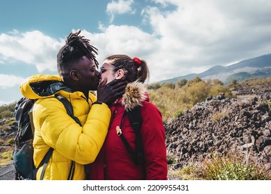 Multiethnic Couple Of Young Hikers On Vacation Kissing Against The Volcano Scenery - Diverse Lovers Trekking And Hugging Against The Volcano Valley - People Wanderlust Lifestyle Concept