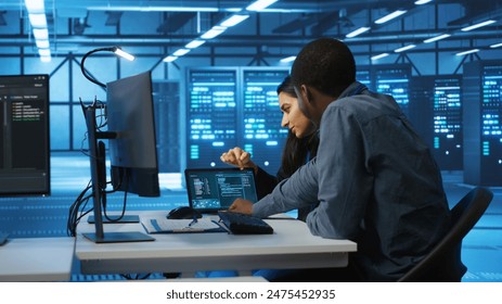 Multiethnic coworkers doing system analysis of server farm supercomputers using tablet. Diverse team of engineers looking at parameters in data center housing storage infrastructure - Powered by Shutterstock