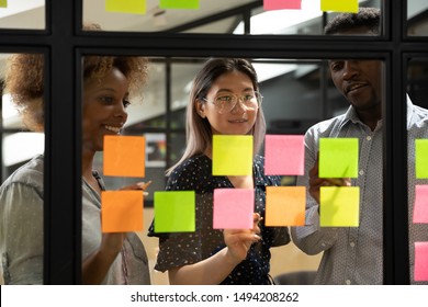 Multiethnic Creative Diverse Young Business Team People Three Colleagues Students Group Brainstorm On Work Plan Talk Write Ideas Tasks On Post It Sticky Notes Look At Glass At Scrum Teamwork Briefing