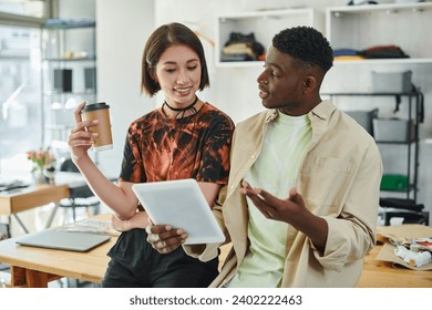 multiethnic designers with digital tablet and coffee to go discussing new project in print studio - Powered by Shutterstock