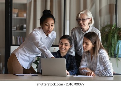 Multiethnic Diverse Business Team Of Female Employees Meeting At Laptop, Looking At Screen, Talking, Discussing Project. Group Leader, Mentor, Coach Explaining And Showing Work Data To Interns