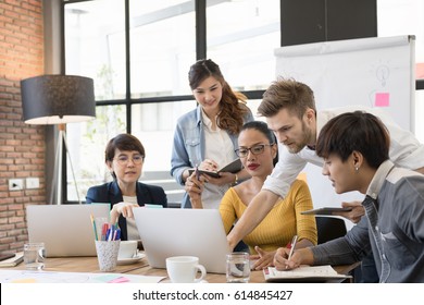 Multiethnic Diverse Group Of Creative Team, Casual Business People In Strategic Meeting Or Project Brainstorm Discussion At Office, Using Smartphone Laptop And Tablet. Startup Or Teamwork Concept.