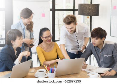 Multiethnic Diverse Group Of Creative Team, Casual Business People In Strategic Meeting Or Project Brainstorm Discussion At Office, Using Smartphone Laptop And Tablet. Startup Or Teamwork Concept.