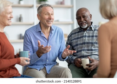 Multiethnic elderly people attending group therapy session at nursing house, positive senior man and woman sitting in circle, drinking tea and having conversation with psychologist, closeup - Powered by Shutterstock