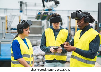 Multiethnic engineers using virtual reality headset inside robotic factory - Industrial and technology concept - Soft focus on african man top hand