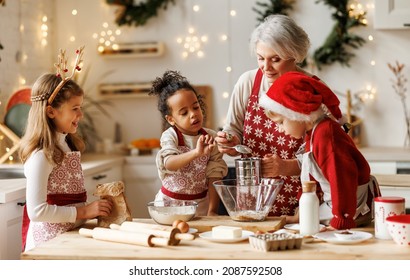 Multiethnic family, grandmother and three little kids, cooking Christmas cookies together in cozy home kitchen for holiday dinner. Multiracial children help grandma with dough preparation on xmas day - Powered by Shutterstock