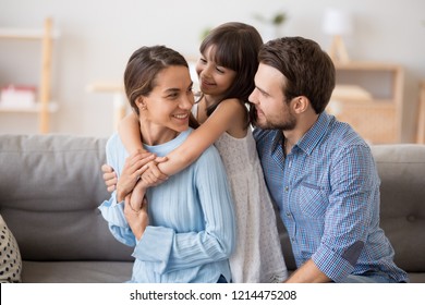 Multi-ethnic family sitting on couch in living room at home enjoy free time together on weekend communicating with each other. Beautiful preschool daughter embrace mother has fun with parents indoors - Powered by Shutterstock