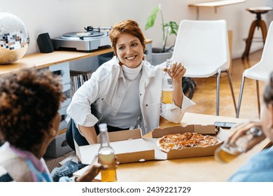 Multiethnic freelance colleagues enjoy a casual pizza lunch in a bright, modern co-working space, fostering teamwork and a relaxed work culture. - Powered by Shutterstock