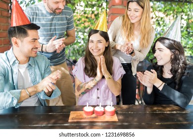 Multiethnic friends clapping during birthday celebration of beautiful woman at outdoor restaurant - Powered by Shutterstock