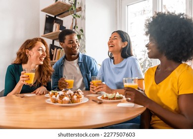 Multiethnic friends having breakfast with orange juice and muffins at home - Powered by Shutterstock