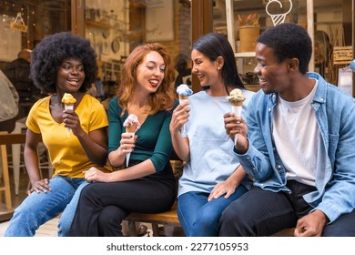 Multi-ethnic friends in an ice cream parlor sitting eating an ice cream, laughing a lot - Powered by Shutterstock