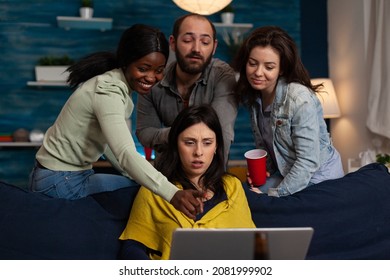 Multi-ethnic Friends Laughing While Watching Online Comedy Movie On Laptop Computer During Entertainment Home Night. Group Of People Enjoying Hanging Out Together. Friendship Concept