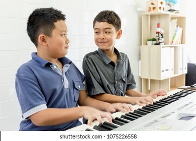 Multiethnic Friends Play Piano Together. Two Boys On Classroom In Music School. Preschool Child Having Fun With Learning To Play Music Instrument. Education, Skills Concept.