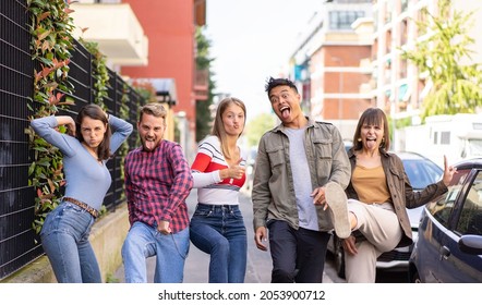 Multiethnic friends walking at sidewalk acting foolish funny moves - Happy guys and girls having fun for weekend on party mood - College students making funny faces looking at the camera - Powered by Shutterstock