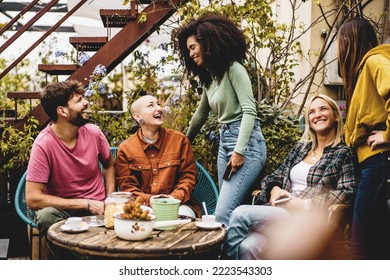 Multiethnic generation z people gathering in the hostel terrace drinking coffee and talking together - diverse community of young friends meets together chatting and having fun in the rooftop garden - Powered by Shutterstock