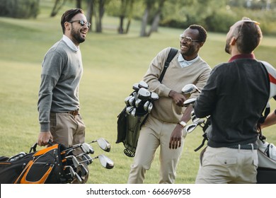 Multiethnic Golf Players With Golf Clubs Having Fun On Golf Course 