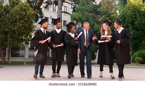 Multiethnic Graduates Students Walking All Together In Front For The Camera After The Graduation Together With The College Principal In The College Garden