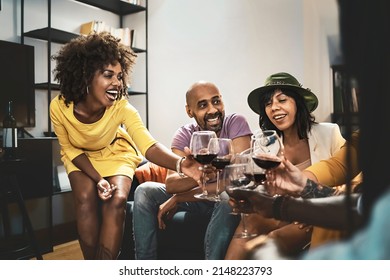 Multi-ethnic Group Of Adult Friends Having Fun Toasting With Red Wine Sitting On The Sofa Indoors - Concept Of Adults Meets In The Weekend Having Fun At Home - Focus On The Curly Woman On The Left