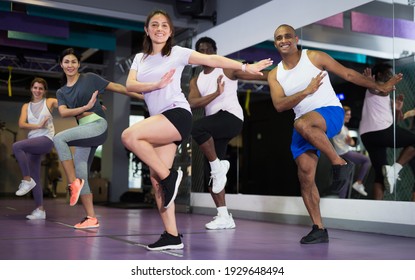 Multiethnic group of adult people practicing active dancing in class at fitness center