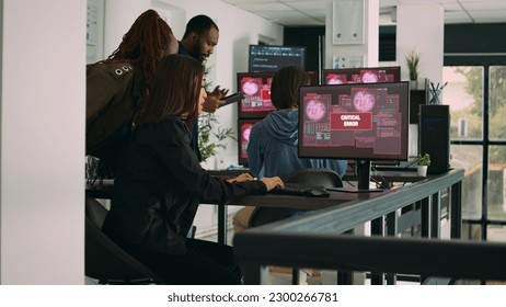 Multiethnic group of app developers reading critical errors on multiple monitors in it agency, being hacked. Working with artificial intelligence code and server database to stop program hacking.