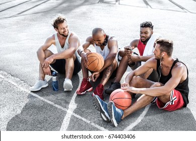 multiethnic group of basketball players resting on court together - Powered by Shutterstock