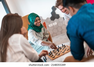 Multiethnic group of business people playing chess while having a break in relaxation area at modern startup office. Selective focus 