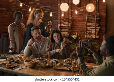 Multi-ethnic group of cheerful adult people taking photo while enjoying party with outdoor lighting - Powered by Shutterstock