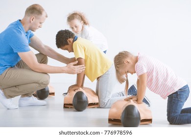 Multiethnic group of children learning on manikins how to give first aid during training with a lifeguard - Powered by Shutterstock