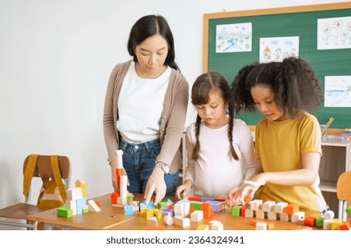 Multi-ethnic group of children school standing and playing with colorful blocks on table with Female Asian teacher in classroom. Education brain training development for children skill concept. - Shutterstock ID 2364324941